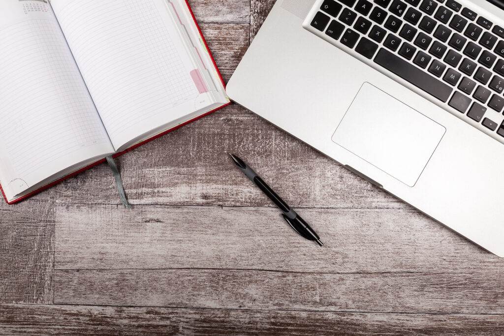 Open writing notebook next to a laptop