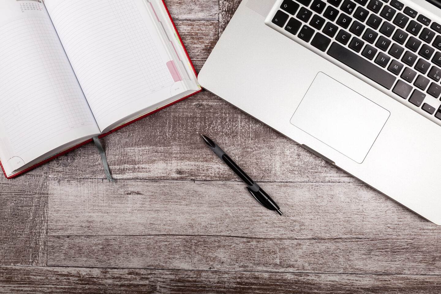 Open writing notebook next to a laptop